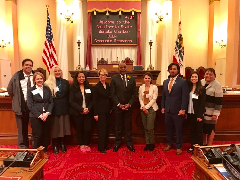 On the floor of the California Senate Chamber. From left to right: Chaitanya Komanduri of UCLA government relations, Shover, Ettner, Keeney-Parks, Garrell, California State Senator Steven Bradford, Rith-Najarian, Gonzalez, Brice, and Ramona Cortés Garza of UCLA Government Relations.