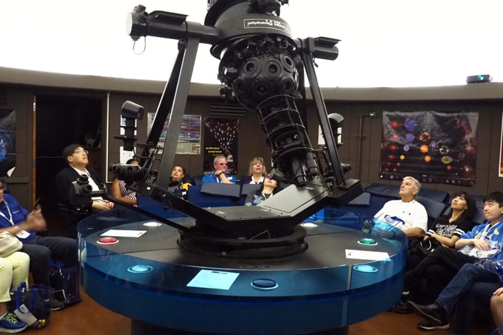 A group of students in UCLA’s planetarium looking up at the projection on the ceiling